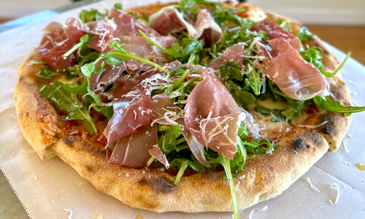 Pizza finished with prosciutto and rocket